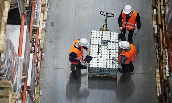 Pallet being loaded in Warehouse with workers checking goods